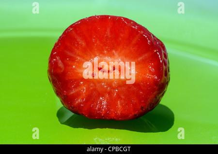 Fragola con un morso prelevato su una piastra verde. Foto Stock