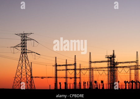 Stagliano tralicci elettrici contro un cielo rosso al tramonto Foto Stock