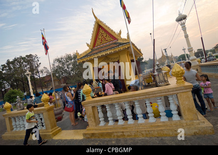 Vista orizzontale di un santuario sul fiume Tonle Sap davanti con molti cambogiani pregando e illuminazione joss-stick. Foto Stock