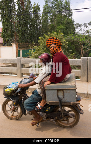 Ritratto verticale di un cambogiano di uomo e di donna alla guida di un ciclomotore lungo una strada di Phnom Penh. Foto Stock