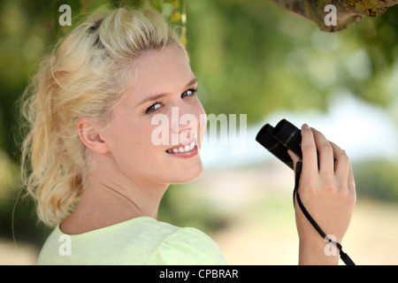 Giovane biondo donna con il binocolo Foto Stock