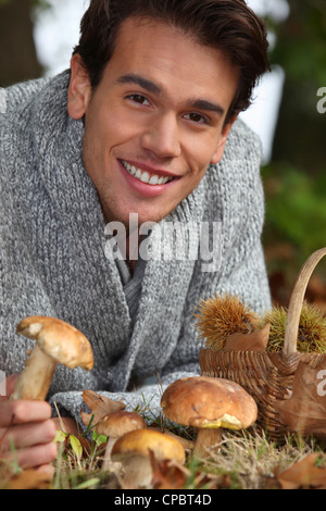 L'uomo la raccolta di funghi e castagne nella foresta Foto Stock
