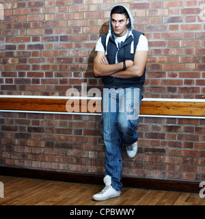 Ritratto di un uomo bianco in un top con cappuccio contro un muro di mattoni di sfondo (non ritoccate). Foto Stock