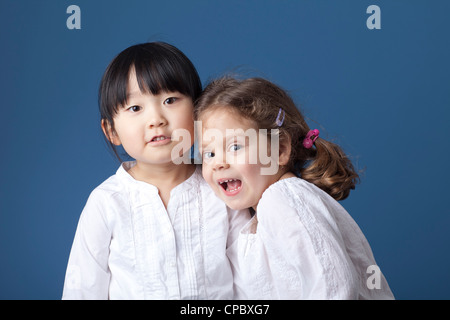 Due bambine shot in studio contro uno sfondo blu. Foto Stock