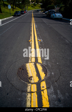 Una disattenzione sostituito chiusino interrompe due linee parallele su una strada di San Clemente, CA. Foto Stock