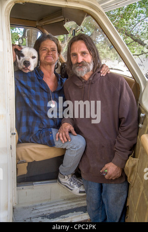 Povero giovane e il loro cane vivere in un camion camper tra sfollati residenti della primitiva di un accampamento all'aperto nel deserto. Foto Stock