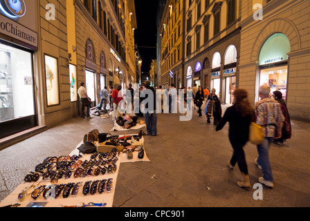 Venditori ambulanti di vendita falsi borsette e occhiali da sole nel centro di Firenze di notte Italia EU Europe Firenze Foto Stock