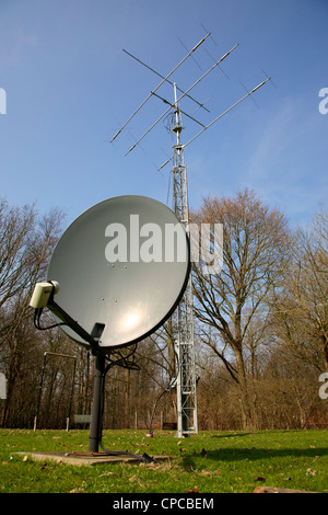 Parabola satellitare e elemento di tre radio HF montante di trasmissione con Yagi e HF Antenna a fascio insieme contro un cielo blu Foto Stock