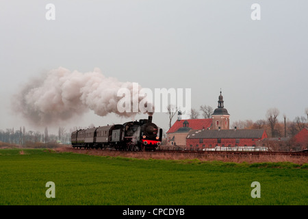 Vapore treno retrò passando il villaggio Foto Stock