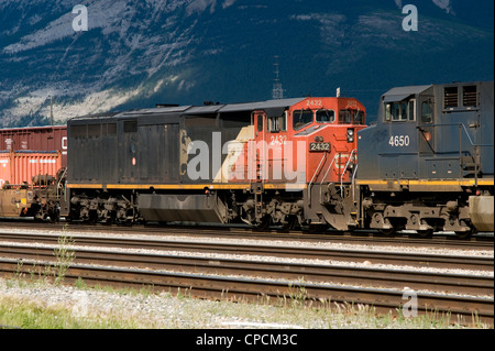 Un Canadian National C40-8M locomotiva aiuta a tirare un treno attraverso Jasper cantiere ferroviario, con un BC locomotore ferroviario in anticipo. Foto Stock