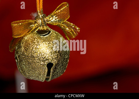 Un bellissimo sfondo di un oro jingle bell su sfondo rosso Foto Stock