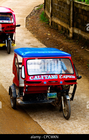 Due taxi triciclo velocità lungo la via principale della città di El Nido sull isola di Palawan nelle Filippine. Foto Stock