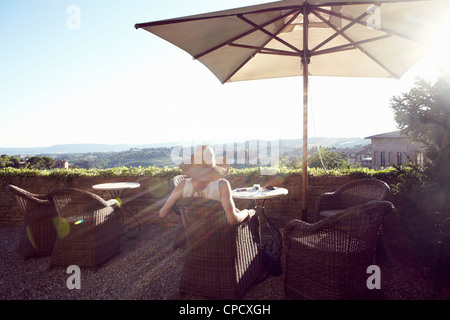 Donna seduta in poltrona sul balcone Foto Stock