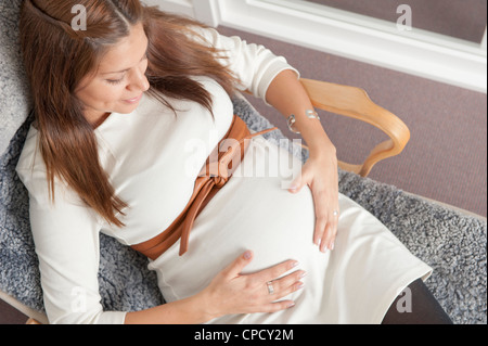 Donna incinta tenendo le mani sul suo stomaco Foto Stock