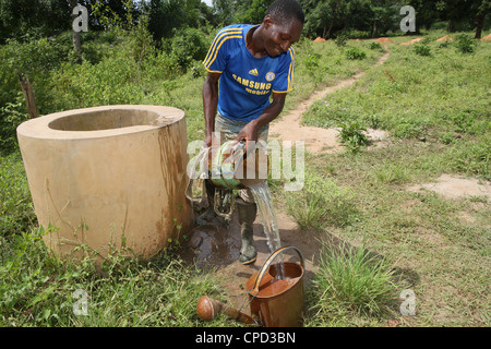L'uomo il recupero di acqua dal bene, Tori, Benin, Africa occidentale, Africa Foto Stock