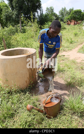 L'uomo il recupero di acqua dal bene, Tori, Benin, Africa occidentale, Africa Foto Stock