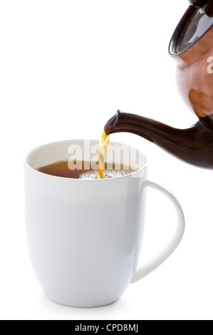 Versando il tè da una teiera in una tazza bianca Foto Stock