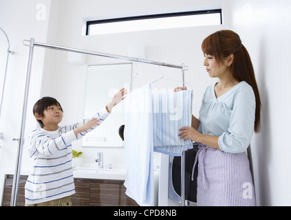 Madre e figlio appendere fuori servizio lavanderia Foto Stock