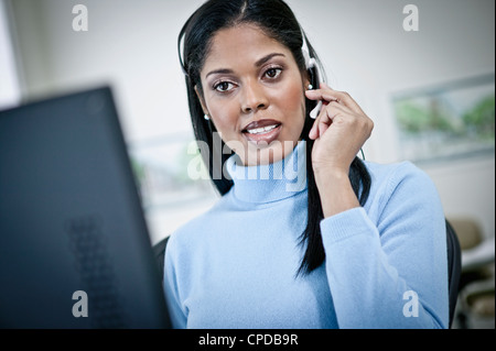 Grave imprenditrice lavorare alla scrivania in cuffia Foto Stock