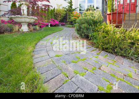 Frontyard pietra cemento lastricatore percorso sul prato verde con fontana di acqua Foto Stock