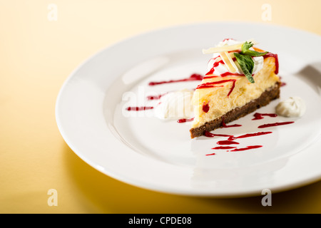 Deliziosa Cheesecake con salsa di lamponi sulla piastra bianca sfondo giallo Foto Stock