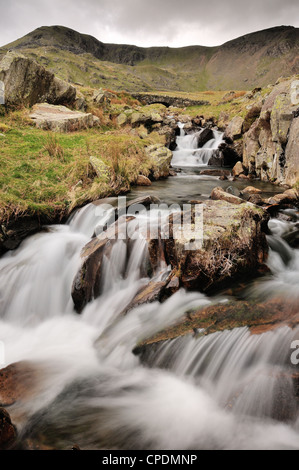 Torver Beck e ponte al di sopra della cicatrice Walna Road nel Lake District inglese, Marrone Pike e Buck Pike in background Foto Stock