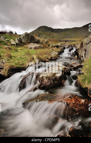 Torver Beck e ponte al di sopra della cicatrice Walna Road nel Lake District inglese, Marrone Pike e Buck Pike in background Foto Stock