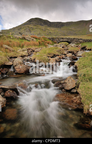 Torver Beck e ardesia tradizionale packhorse ponte al di sopra della cicatrice Walna Road nel Lake District inglese Foto Stock