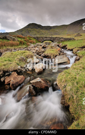 Torver Beck e ardesia tradizionale packhorse ponte al di sopra della cicatrice Walna Road nel Lake District inglese Foto Stock