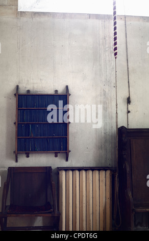 Chiesa interno con scaffale per libri di preghiera comune, sedia e il radiatore. Foto Stock