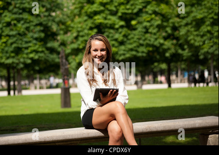 Giovane donna in possesso di una tavoletta digitale all'esterno. Foto Stock