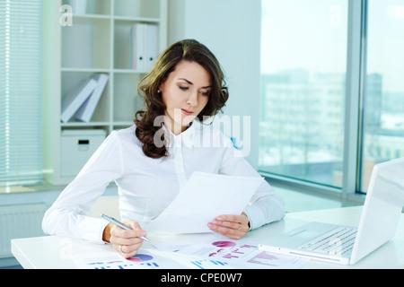 Business lady guardando attraverso le carte e prendere note Foto Stock