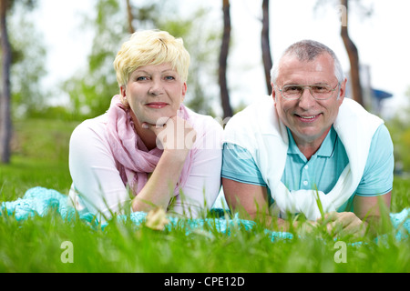 Felice Coppia matura giacente su erba e avente il resto in estate Foto Stock