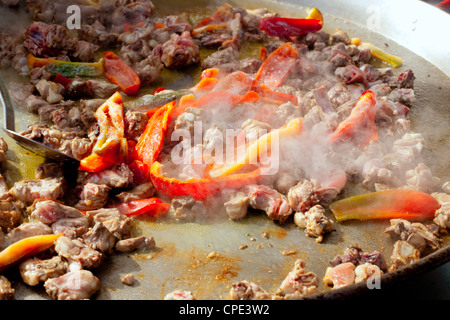 La paella dalla Spagna i primi passi per la cottura grande padella con pollo e pepe rosso Foto Stock