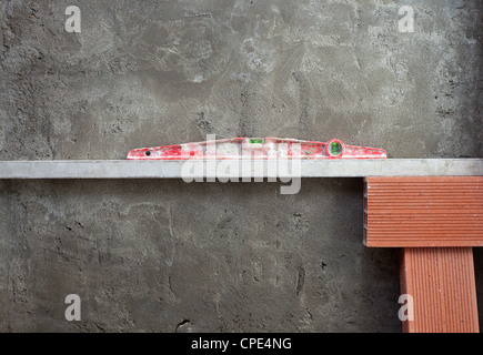 Bolla di livello di spirito utensile in rosso sulla costruzione parete in cemento con mattoni Foto Stock