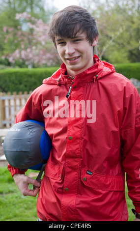 Modello rilasciato immagine del giovane uomo che indossa red kagoule giacca e tenendo il sacco a pelo Foto Stock