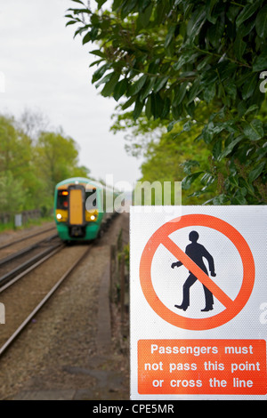 Segnaletica di pericolo: i passeggeri non devono superare questo punto o attraversare la linea. Con una ferrovia veloce Treno in avvicinamento Foto Stock