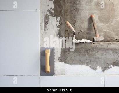 Strumenti di costruzione cazzuola dentellata su piastrelle parete di malta Foto Stock