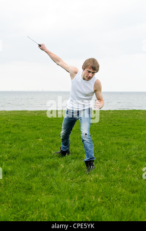 Uomo con coltello militare in riva al mare Foto Stock