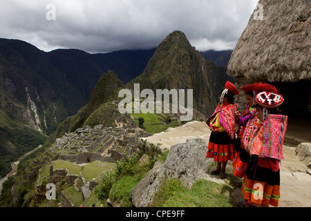 Tradizionalmente i bambini vestiti alla ricerca sulle rovine della città Inca di Machu Picchu, montagne Vilcabamba, Perù Foto Stock