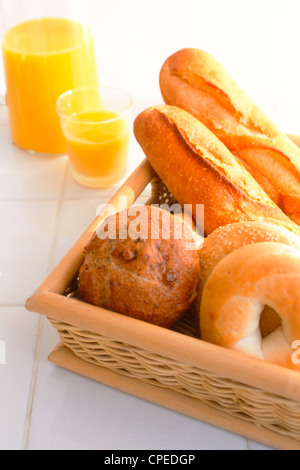 Un assortimento di pane in vassoio di legno e succo di arancia Foto Stock