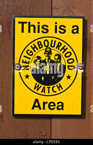 Un giallo Neighborhood Watch strada segno su una recinzione marrone Foto Stock