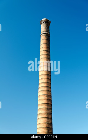 Industriali ciminiera in mattoni contro il blu intenso del cielo. Foto Stock