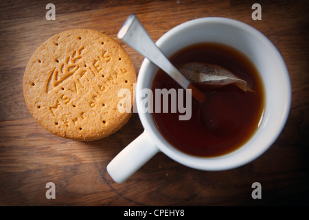 Digestive McVities biscotti e una tazza di tè sul piano di lavoro in legno Foto Stock