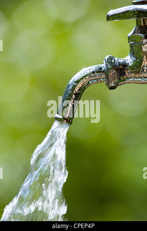 Esecuzione di acqua dal rubinetto con sfocatura sullo sfondo Foto Stock