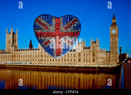 A forma di cuore frizzante riflettente Union Jack Flag motif con le case del Parlamento dietro Westminster London REGNO UNITO Foto Stock