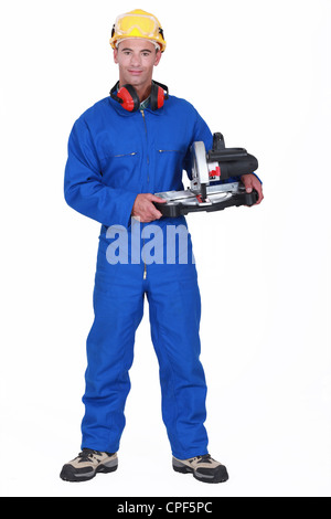 Tuttofare tenendo una sega circolare Foto Stock