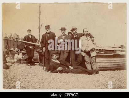 Foto originale degli uomini edoardiani posano accanto ad una barca da pesca su una spiaggia di ghiaia, possibilmente Devon. Inghilterra, Gran Bretagna, Regno Unito, Regno Unito, circa 1910 Foto Stock