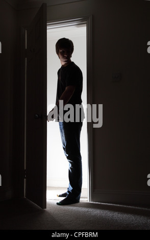 Silhouette di un giovane maschio di apertura di una porta. Foto Stock