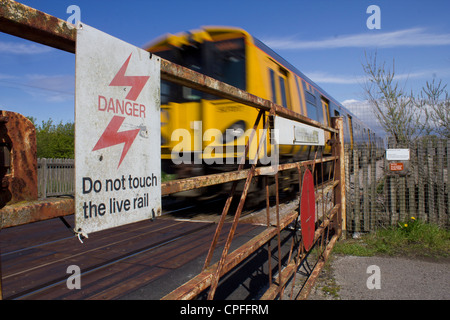 Un velocizzando il treno passa un unmanned passaggio a livello ferroviario Foto Stock